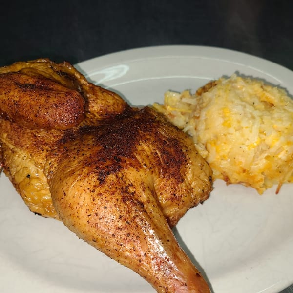 Papas Bar's grilled chicken with crispy skin and a side of cheesy hash browns on a white plate.