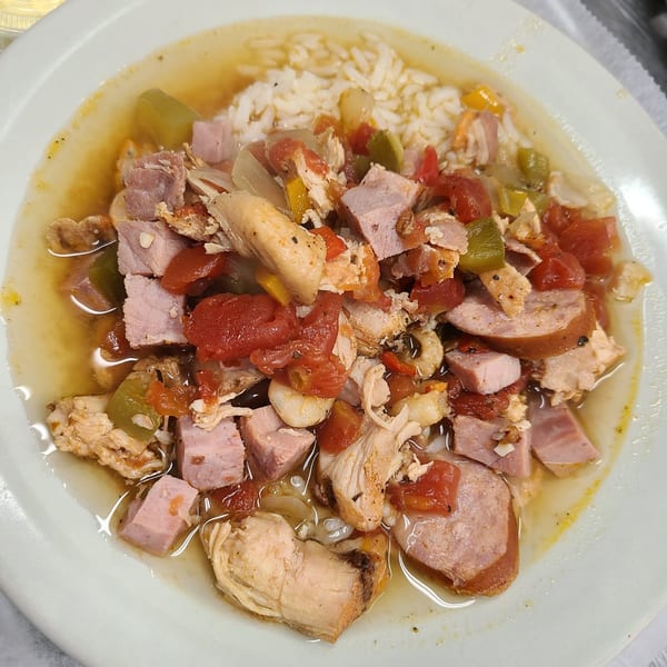 A bowl of Papas Bar's gumbo with chicken, sausage, ham, rice, and vegetables in broth.